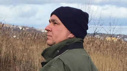 Person in black ski cap standing in a field looking left