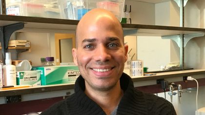 Person with shaved head in front of lab bench