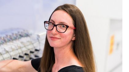 Person with shoulder-length hair holding pipette at a bench.