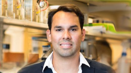 Person with short haircut standing in front of a lab bench.