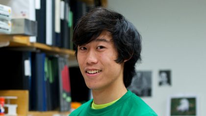 Person with black hair and green sweatshirt in front of lab bench