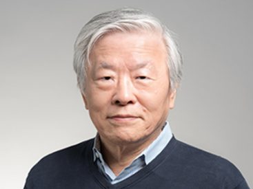 Person with white hair in blue sweater against grey backdrop