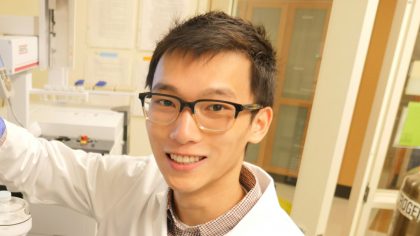 Person with short, dark hair and glasses in lab coat