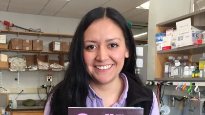 Person with long, dark hair smiling in lab