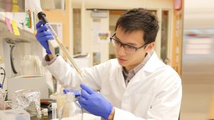 Student in lab coat pipetting