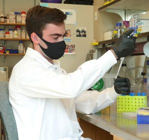 Man with mask pipetting in lab