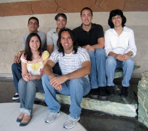 Five people sitting on a rock smiling