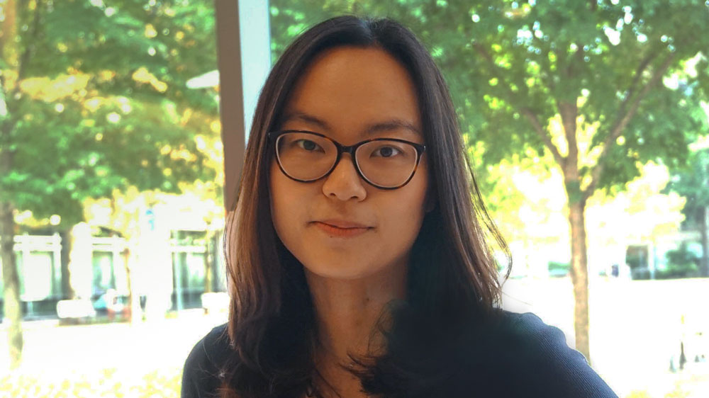 Person with glasses smiling by window