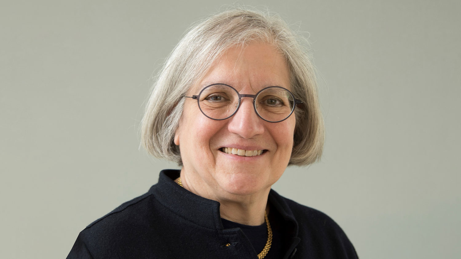 Woman with grey hair and glasses smiling