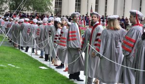 Line of grad students in cap and gown outside