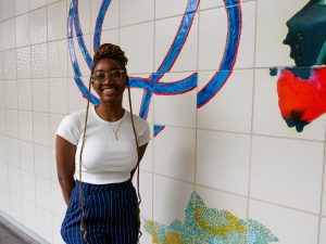 woman standing in front of patterned wall, smiling