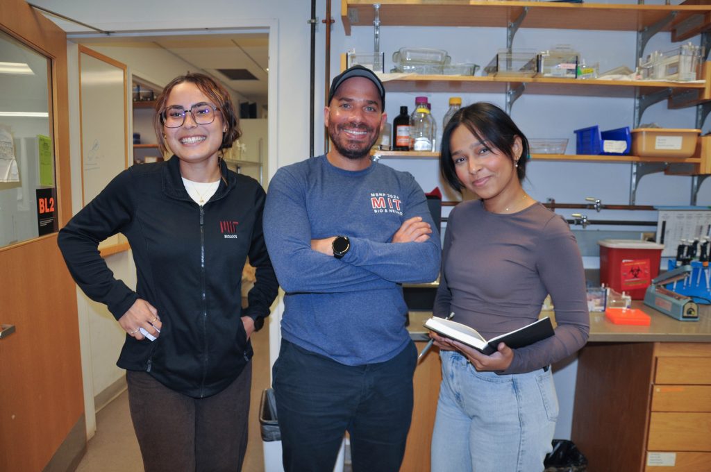 Three people standing in an interior lab space smiling at the camera